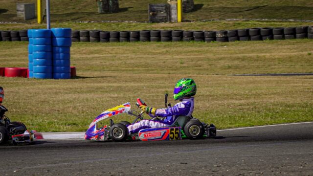 A child in a go-kart races on a track.