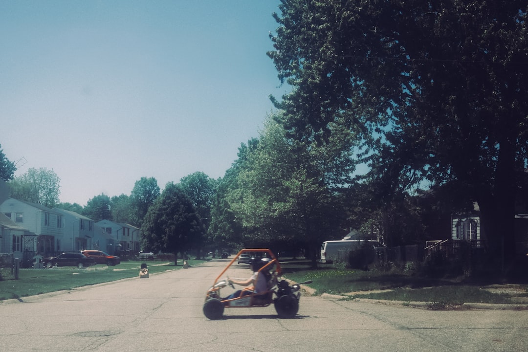 A person drives a go-kart down a residential street.