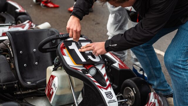 Person adjusting a go-kart with number 13.