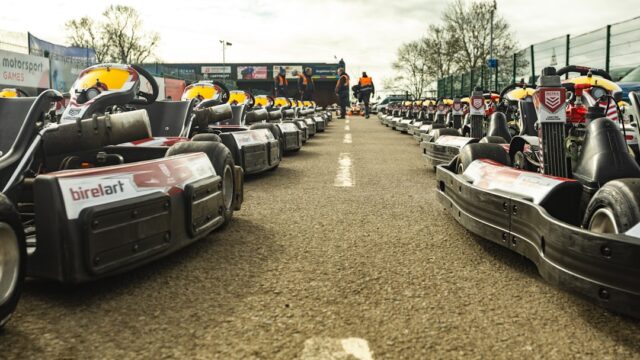 Two rows of go-karts lined up on an asphalt track.