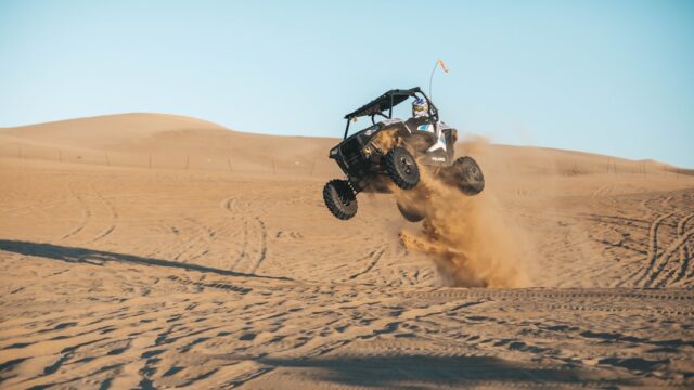 man riding on UTV on desert during daytime