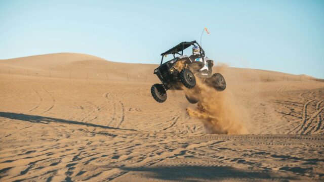 man riding on UTV on desert during daytime