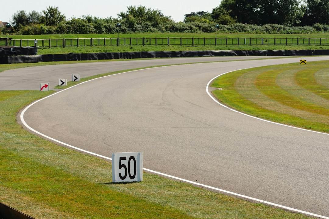 Empty asphalt race track curving through green grass